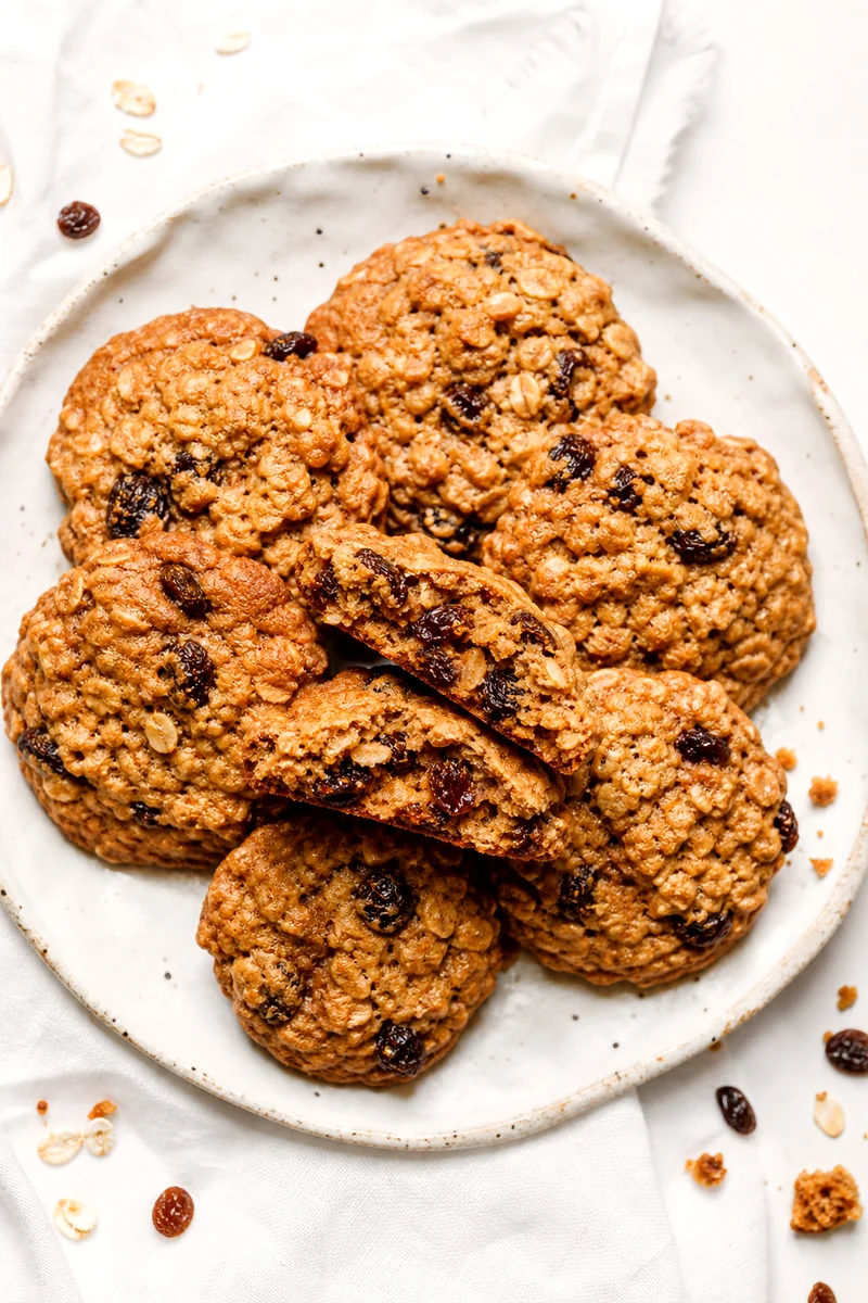Oatmeal raisin cookies on a white plate with one cookie broken open