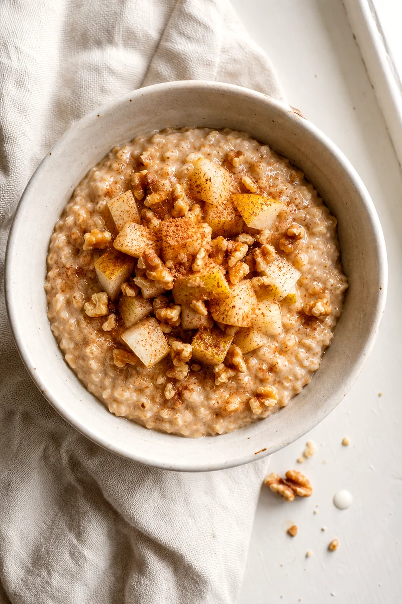 Top down view of pear cinnamon oatmeal with walnuts and cinnamon in a white bowl