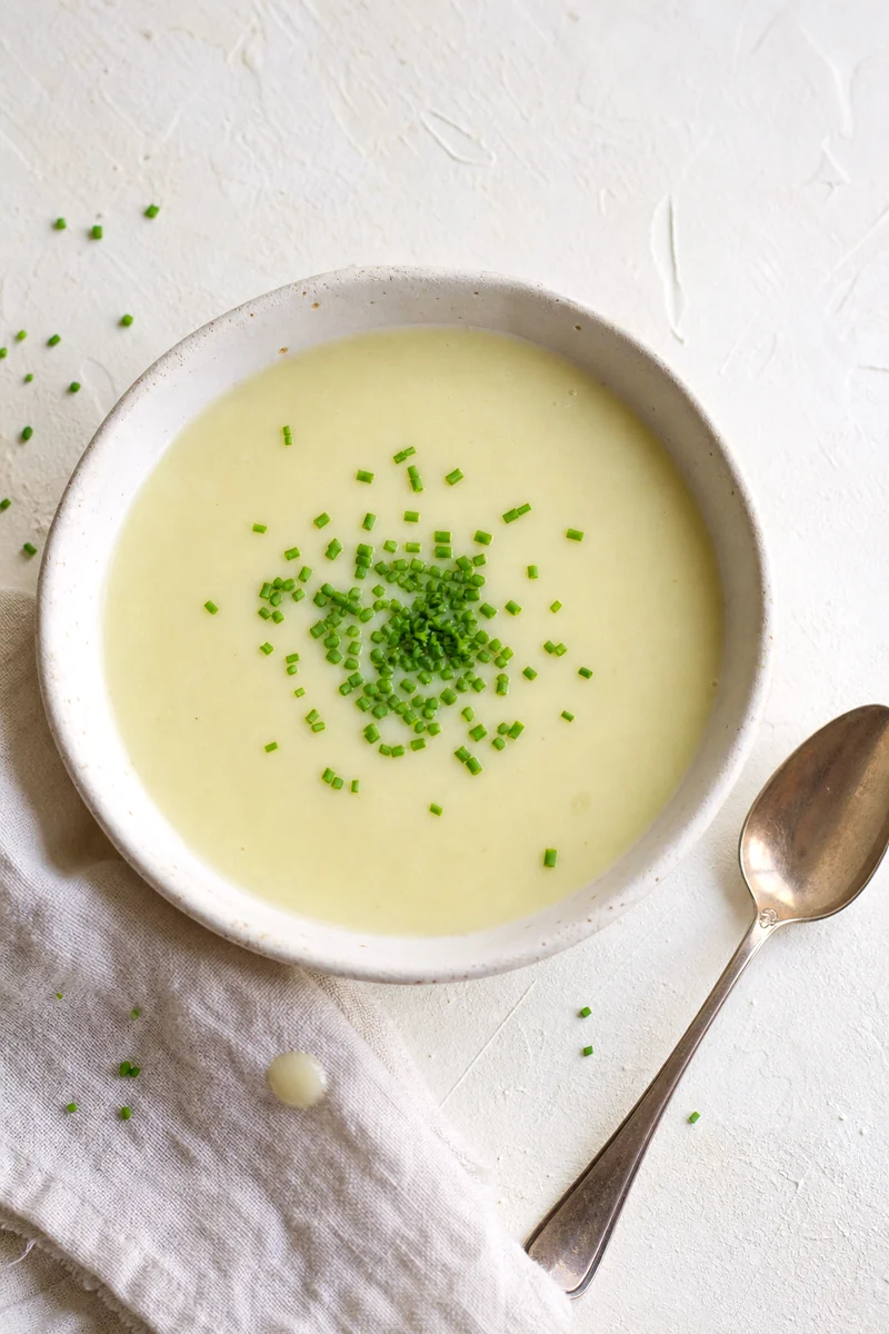 Creamy chilled vichyssoise topped with chives in a white bowl seen from above