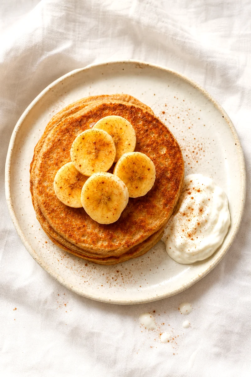 Top view of fluffy whole wheat banana pancakes with yogurt, banana slices, and cinnamon